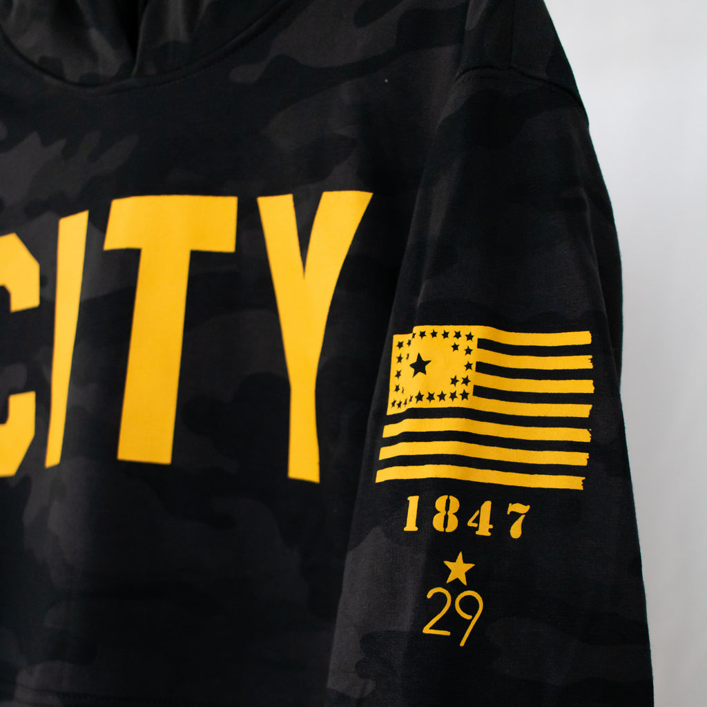 black military camo hooded sweatshirt city printed in gold on front 29 star flag university of iowa established year and 29th state apparel logo all printed in gold on left sleeve
