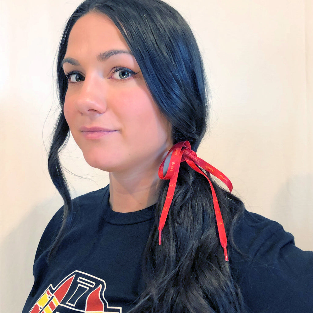 A young woman with long black hair and her hair is tied up on the side with a red shoelace