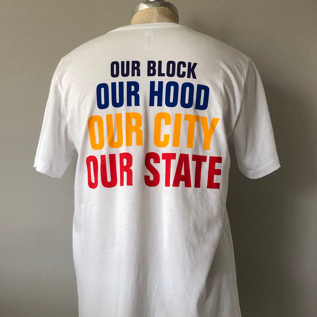 a basic white tee on a mannequin showcasing the back of the t-shirt with "OUR BLOCK OUR HOOD OUR CITY OUR STATE" descending down the back