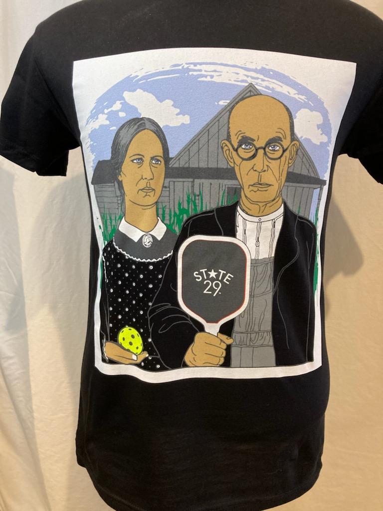 A black short sleeve t-shirt featuring the historical American Gothic picture with corn a pickleball and pickleball paddle added and the 29th state apparel logo on the paddle