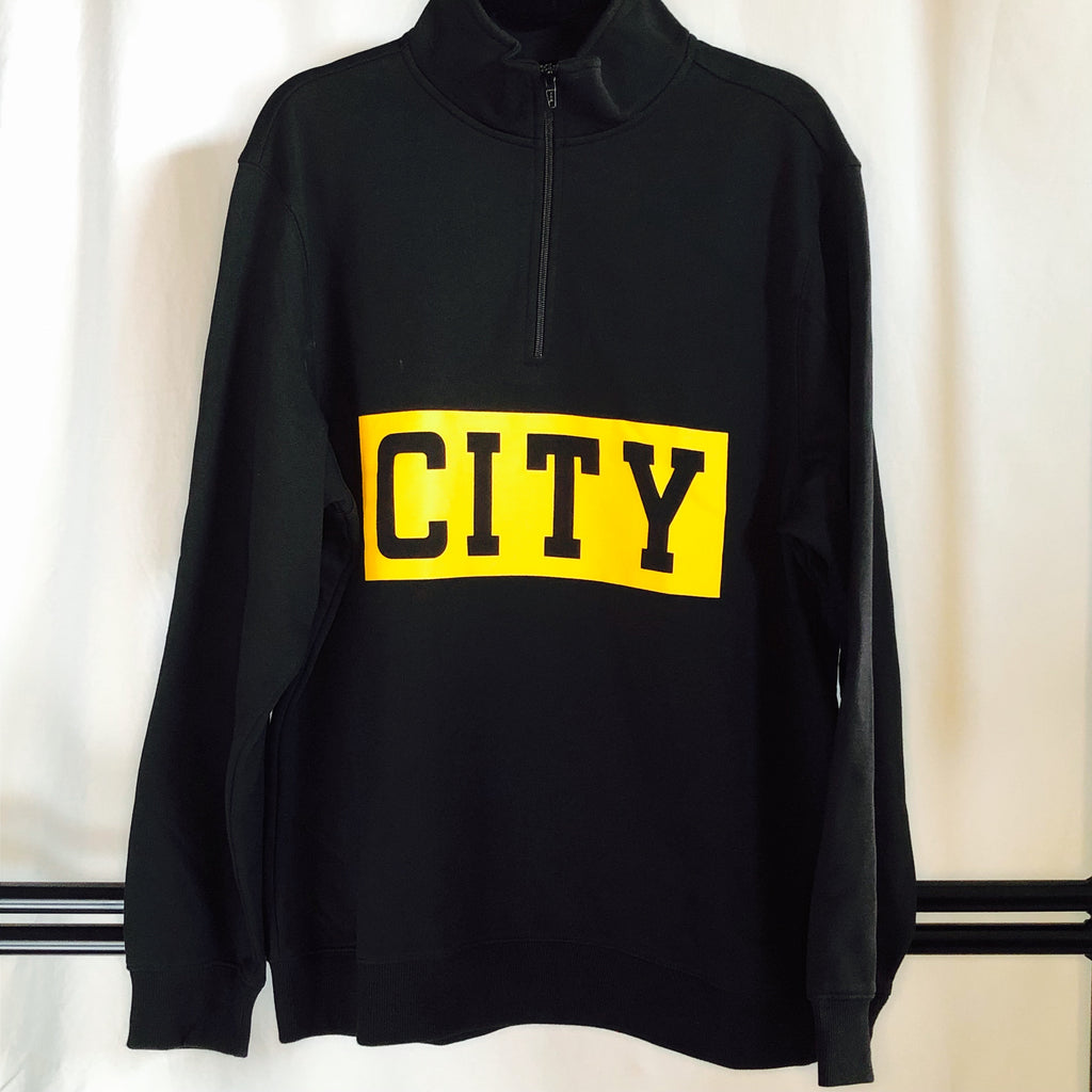 a black 1/4-zip sweatshirt zipped all the way up hanging from a hanger and showcasing a thick, bold and gold stripe across the front with "city" cut out of the gold in black