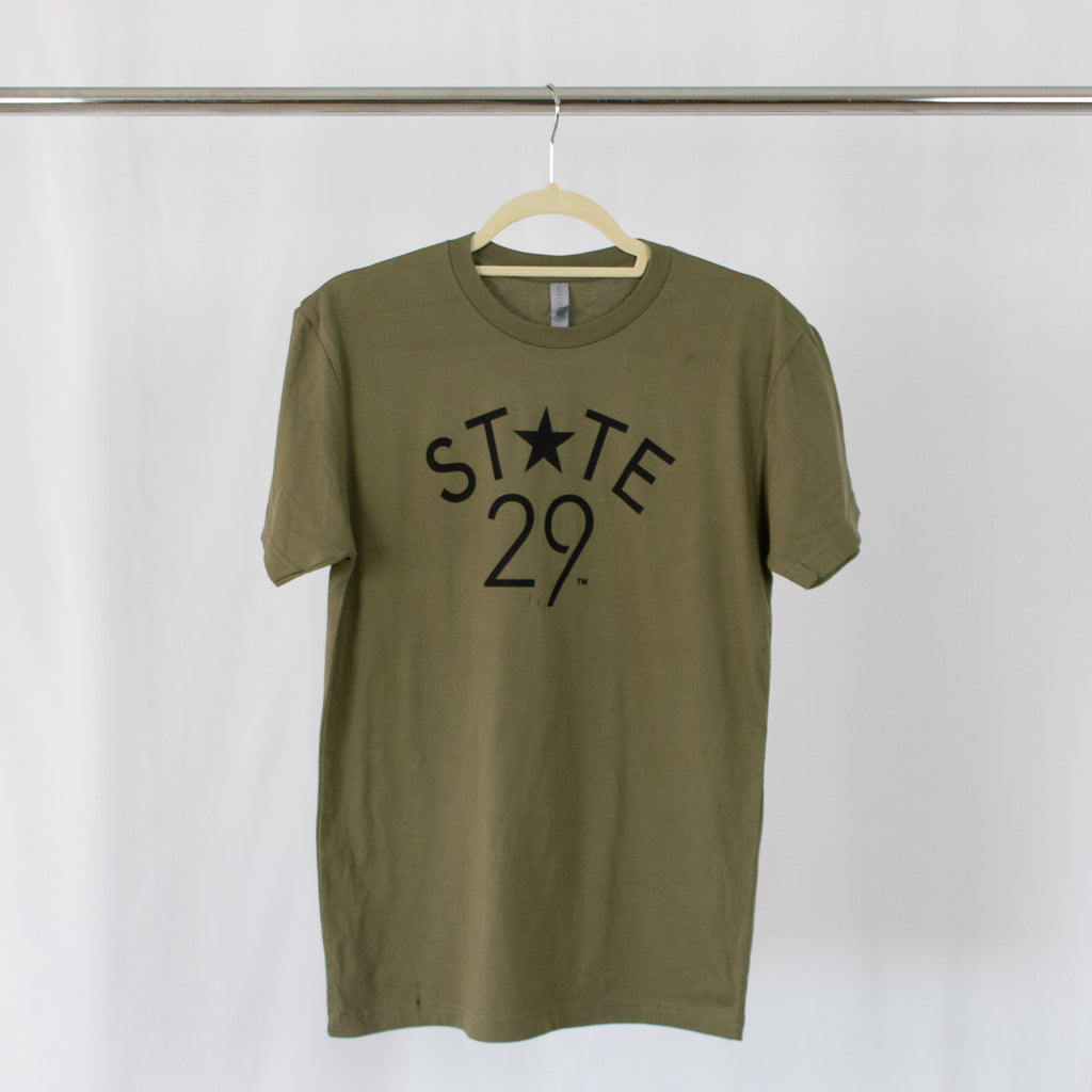 olive green tee shirt with black 29th state apparel logo on front center hanging from silver rack