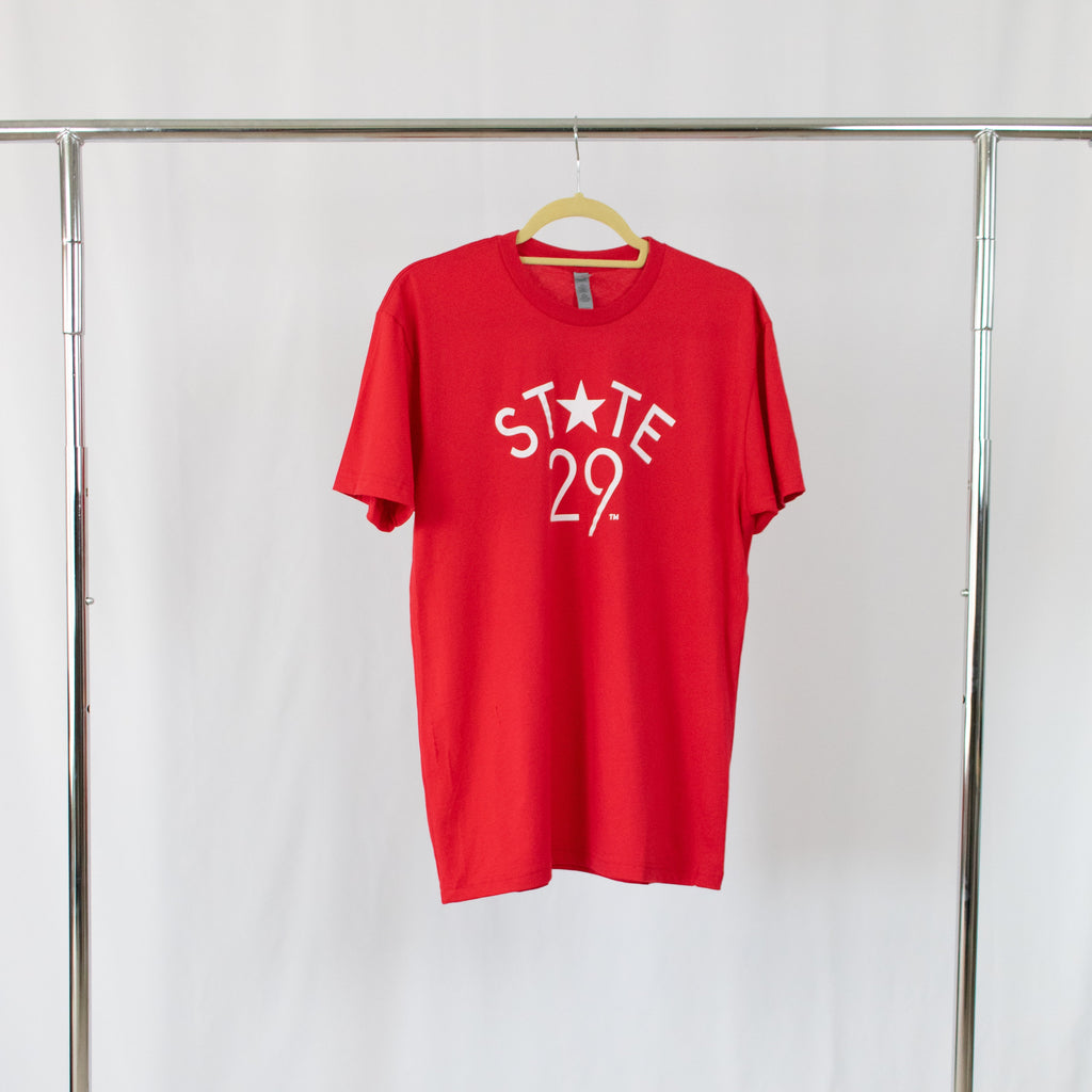 a red tee shirt with a white 29th state apparel logo on front center hanging from a silver rack