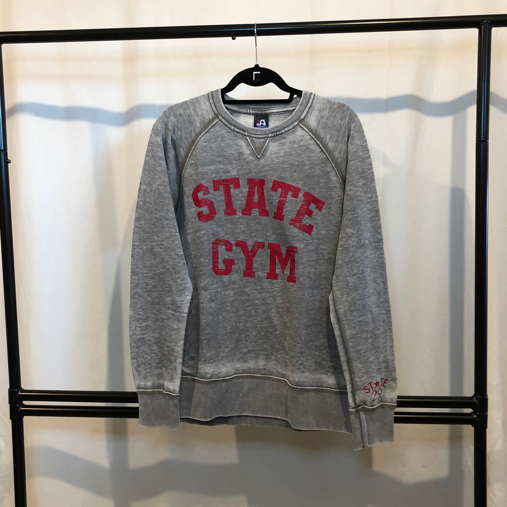 A vintage looking crewneck sweatshirt hanging on the hanger on a black rack the sweatshirt is light grey "cement" with red "STATE GYM" screenprinted on the front in bold all cap lettering