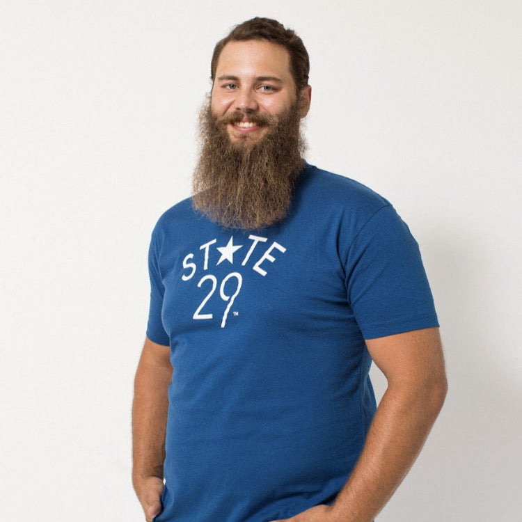 tall long bearded young man wearing a cool blue 29th state apparel logo tee